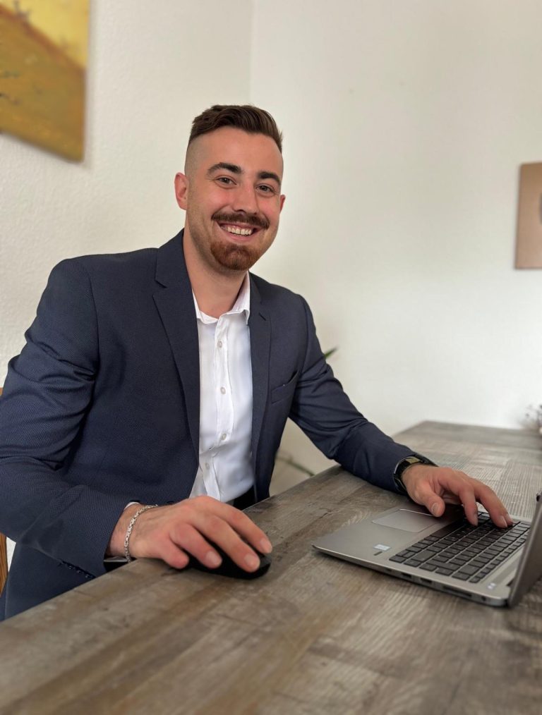 Beratung mit Herz und Verstand Elias Grabner sitzt lächelnd am Schreibtisch vor einem Laptop – persönliche Energieberatung auf Augenhöhe.